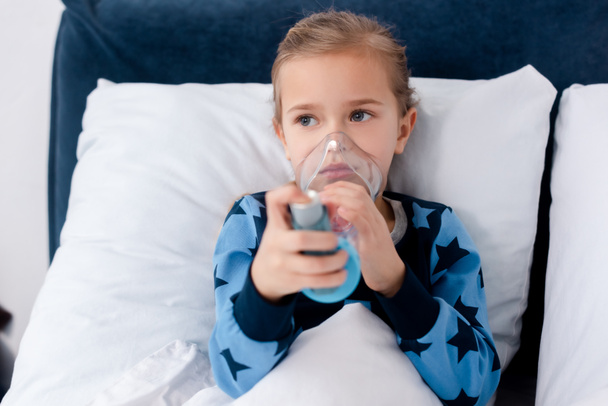Krankes Kind mit Inhalator mit Abstandhalter im Schlafzimmer - Foto, Bild