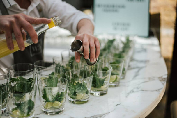 A closeup shot of a barman making lime mojitos on a marble bar stand - Foto, Imagen