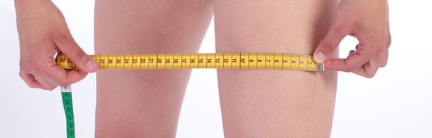 Closeup photo of a Caucasian woman's leg and measuring tape - Foto, afbeelding
