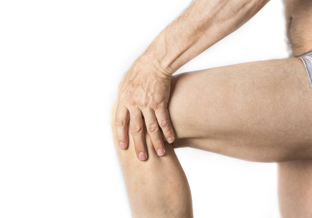 Человек держит больное колено рукой
 - Фото, изображение