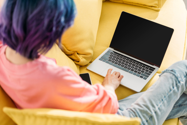 Selective focus of freelancer with colorful hair and laptop sitting on sofa - Photo, Image