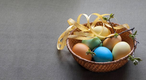 Easter composition with colored eggs, a yellow ribbon, branches with young leaves - Foto, immagini