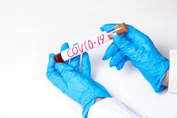 Coronavirus Covid 19 infected blood sample in sample tube in hand of scientist doctor biohazard protection clothing in coronavirus covid 19 research laboratory - Фото, изображение