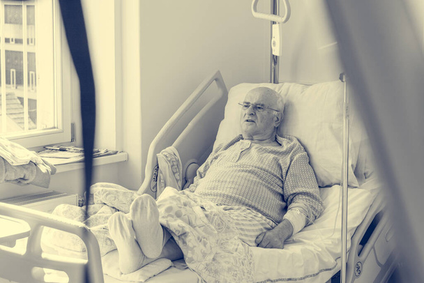 Anciano acostado en una cama en el hospital
. - Foto, Imagen