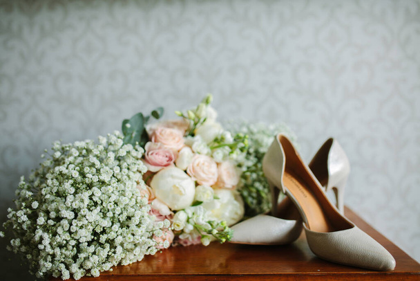 pies femeninos en sandalias de boda blancas con un ramo de manzanillas
 - Foto, Imagen