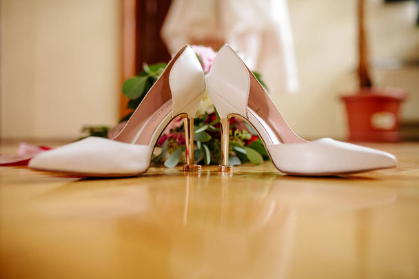 female feet in white wedding sandals with a bouquet of camomiles - Photo, Image
