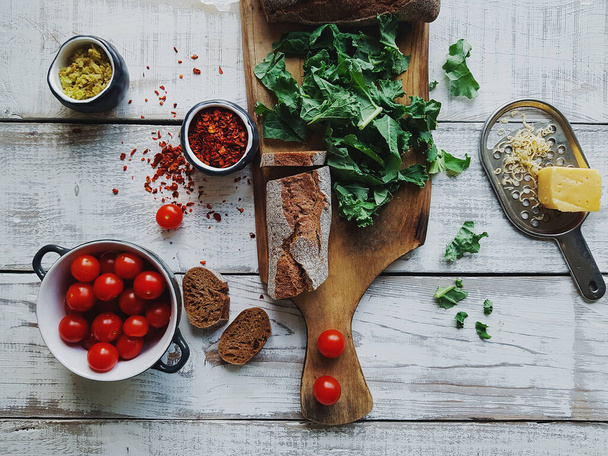 Ingredienti per insalata, pasta o pizza italiana, pomodorini, formaggio, spezie ed erbe aromatiche su tavola rustica in legno, vista dall'alto
 - Foto, immagini