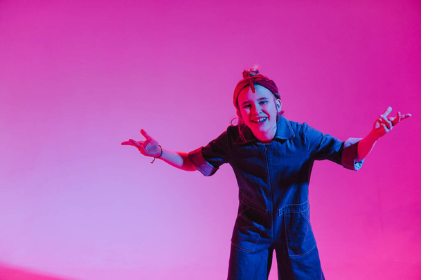Молодая стильная девушка танцует в студии на цветном неоновом фоне. Дизайн музыкального плаката
. - Фото, изображение