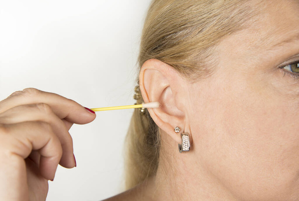 Frau putzt sich mit Abstrich das Ohr - Foto, Bild