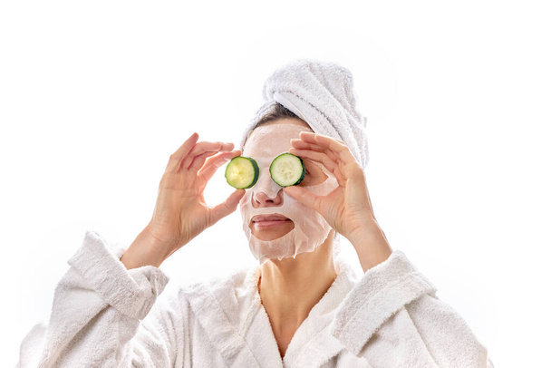Yüz maskesi ve salatalık dilimi olan bir kadın gözlerini düzeltiyor. Gözlerinin etrafındaki ten rengi. Olgun, güzel, temiz ten.. - Fotoğraf, Görsel