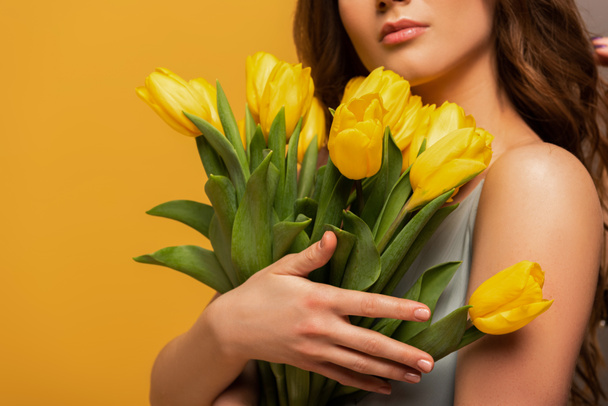Kırpılmış bahar elbisesi giymiş bir kızın elinde sarı renkli bir lale çiçeği buketi vardı. - Fotoğraf, Görsel