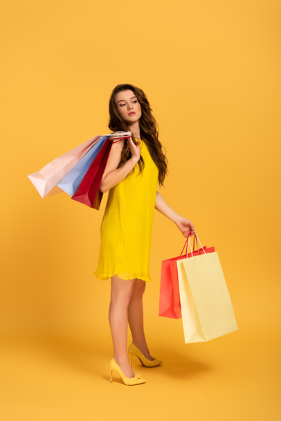 beautiful girl in spring dress holding shopping bags on yellow - Photo, image