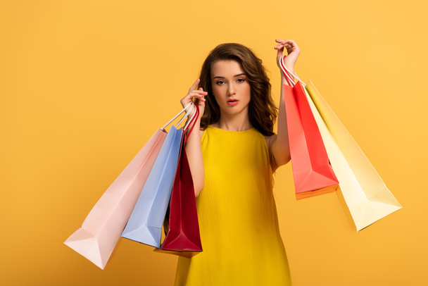 beautiful elegant girl in spring dress holding shopping bags on yellow - Zdjęcie, obraz