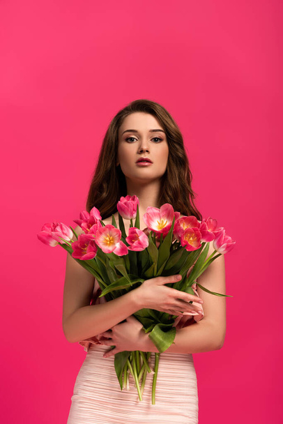 attractive girl holding bouquet of spring tulip flowers isolated on pink - 写真・画像