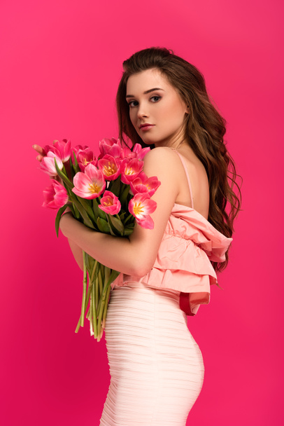 attractive woman in elegant dress holding bouquet of spring tulips isolated on pink - Valokuva, kuva