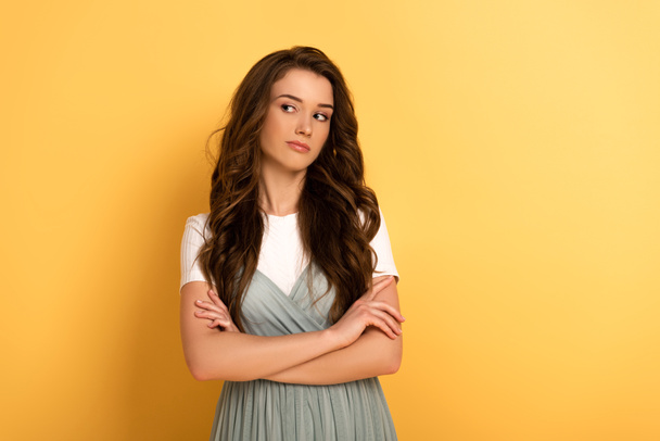 attractive thoughtful spring girl with crossed arms on yellow - Foto, Imagen