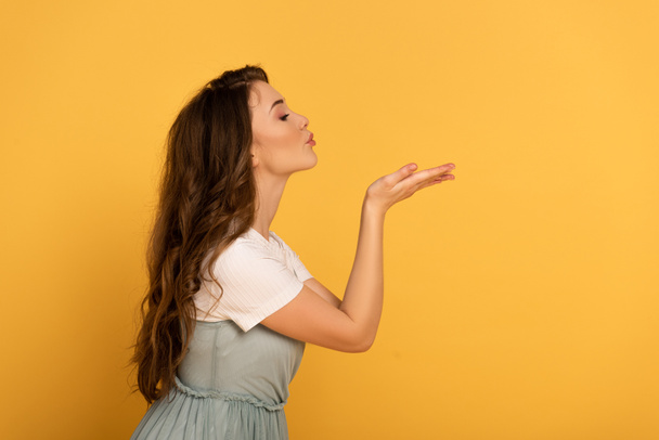 beautiful elegant spring girl blowing air kiss on yellow - Valokuva, kuva