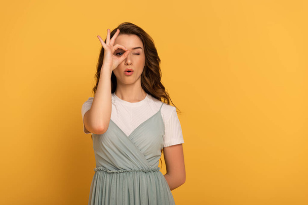 attractive shocked girl showing ok sign on yellow - Foto, Bild