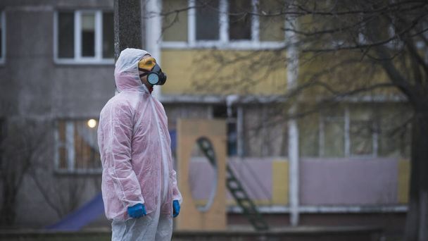 The young europeans man in protective chemical suit and respirator, outdoors. New coronavirus (COVID-19). Concept of health care during an epidemic or pandemic - Zdjęcie, obraz