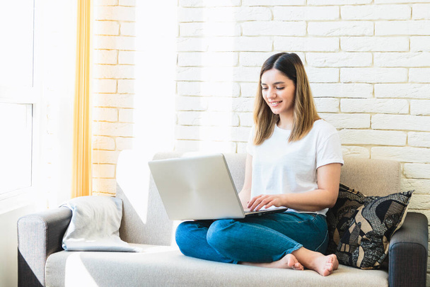 Otthon dolgozom. fiatal gyönyörű nő dolgozik laptop kanapén otthon, míg a karanténban, mert a világjárvány vírus. - Fotó, kép