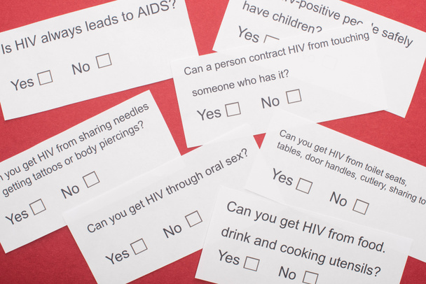 pohled shora na papírové karty s dotazníkem HIV na červeném pozadí - Fotografie, Obrázek
