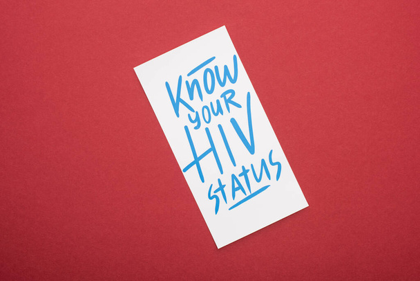 vista superior do cartão com saber o seu status de HIV lettering no fundo vermelho
 - Foto, Imagem