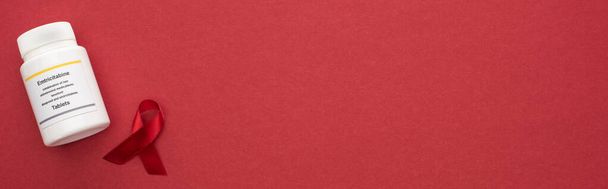 vista superior de la conciencia roja ayuda cinta y emtricitabina tabletas sobre fondo rojo, plano panorámico
 - Foto, Imagen