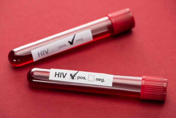 selectieve focus van negatieve en positieve hiv bloedmonster test op rode achtergrond - Foto, afbeelding