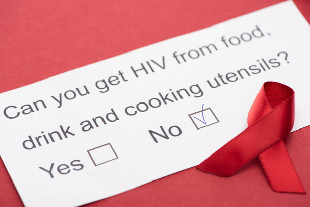 paper card with HIV questionnaire with awareness ribbon on red background - Fotoğraf, Görsel