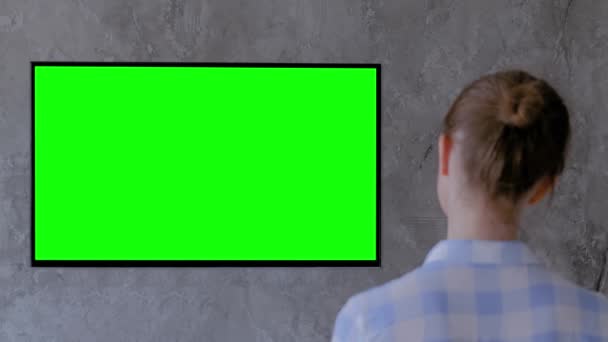 Koncepcja zielonego ekranu - kobieta ogląda płaski telewizor LED z zielonym wyświetlaczem - Materiał filmowy, wideo
