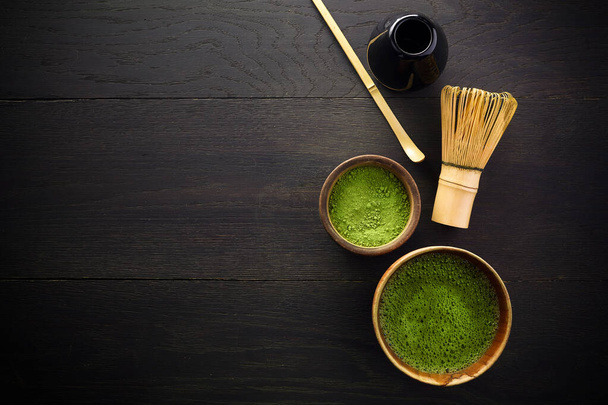 抹茶パウダー。有機抹茶茶道。健康的な飲み物だ。黒木の背景に伝統的な日本酒 - 写真・画像
