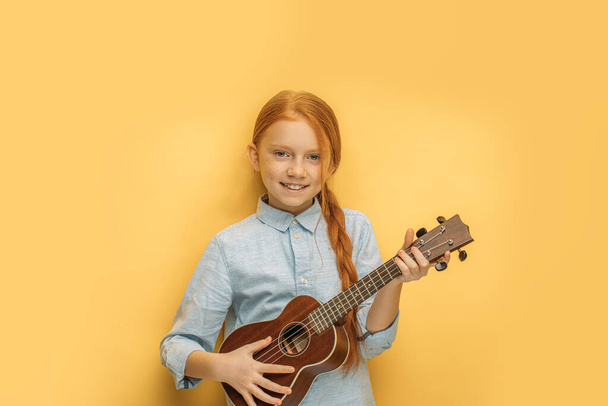 beautiful girl learns to play ukulele - Foto, afbeelding