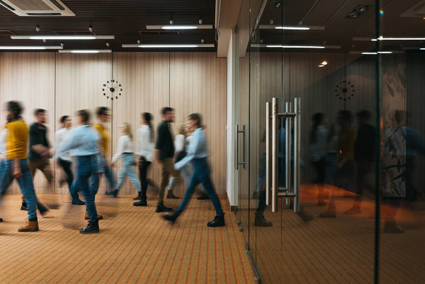 Grupo de empleados de oficina en la sala de coworking. Gente de negocios caminando en el espacio abierto moderno. Desenfoque de movimiento. Concepto
 - Foto, Imagen