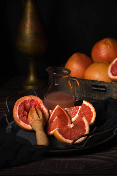 Kawałki świeżych grejpfrutów przygotowane do wyciskania świeżego soku na talerzu, ciemne tło - Zdjęcie, obraz