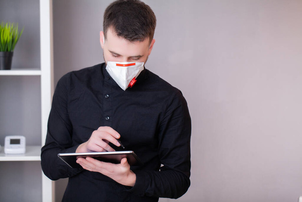 Man die in het kantoor werkt en een masker draagt ter bescherming tegen coronavirus - Foto, afbeelding