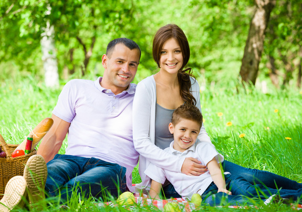 Happy family of three has picnic in green park - Фото, зображення