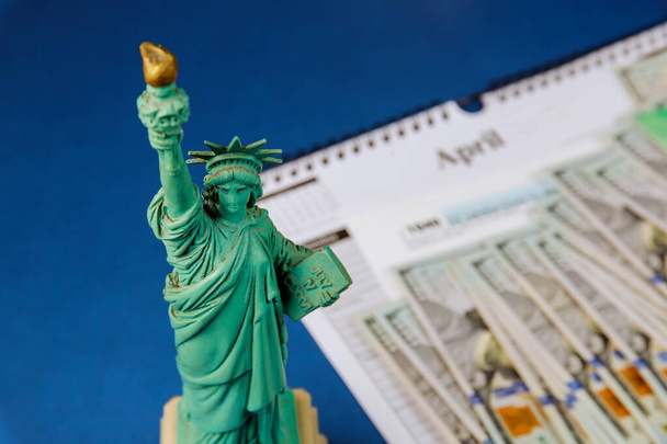 Estátua Liberdade no período fiscal nos EUA com 1040 US forma de imposto, dinheiro e calendário dólares dos EUA declaração de imposto de dinheiro
 - Foto, Imagem