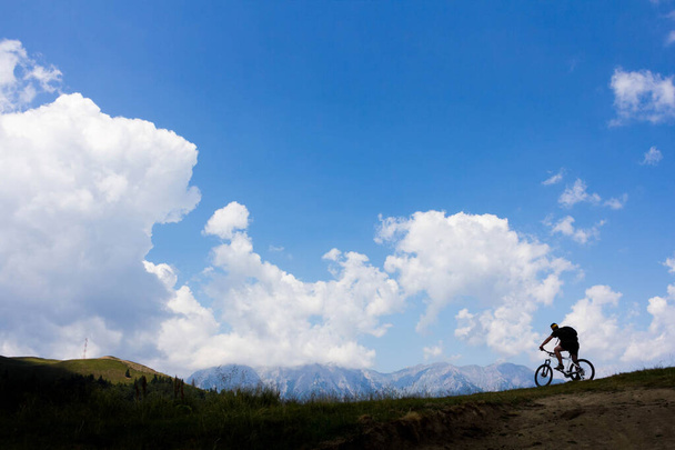 Distant photo of man riding bike in the mountains - Photo, Image