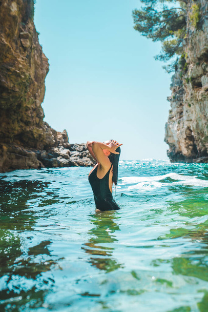 młoda seksowna kobieta w czarnym stroju kąpielowym w czystym błękitnym morzu woda ciało kształt lato plaża wakacje - Zdjęcie, obraz