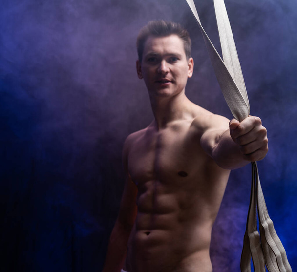 Muscular male circus artist with aerial straps on black and smoked background - Foto, Imagem