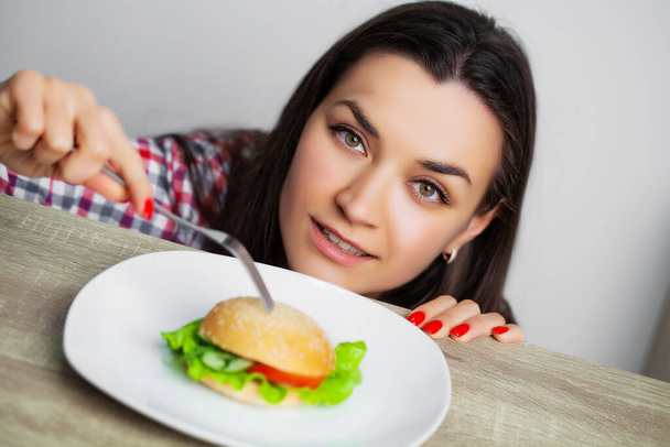 Cute woman wants to eat hamburger harmful - Фото, изображение