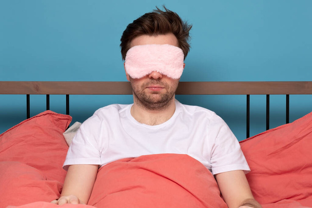 Кавказький зрілий чоловік з рожевою маскою спить лежачи в ліжку сам. Студійні зйомки - Фото, зображення