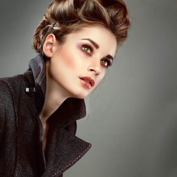 Portrait of elegant young woman in a grey overcoat on a grey background - Foto, Imagem