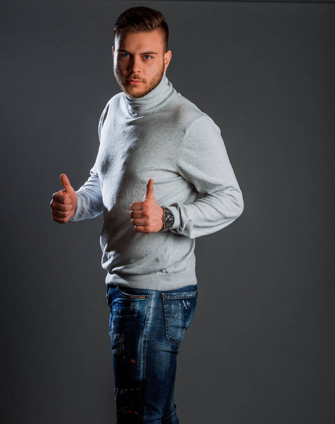 Attraktiver junger, stylischer Mann posiert in Strick-Polohemd und Jeanshose - Foto, Bild