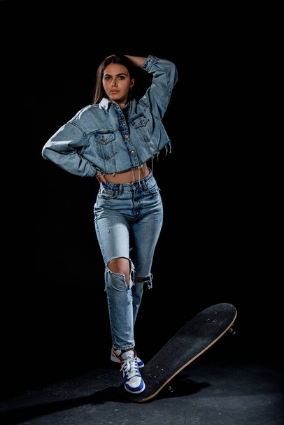 Κομψό κορίτσι της μόδας φορώντας μοντέρνα ρούχα που θέτουν με ένα skateboard - Φωτογραφία, εικόνα