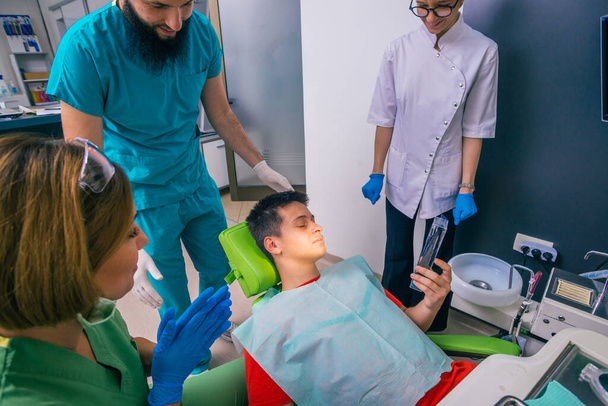 Tinédzser fiú beteg ül a fogorvosi széken nézi a fogászati berendezések - Fotó, kép