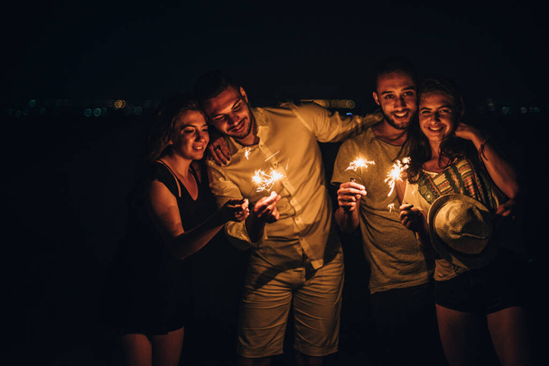 heerful young people hanging out at night. Best friends having a party with sparklers - Foto, Imagen