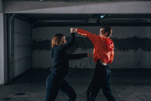 Zwei Sportlerinnen zeigen technisches Geschick beim Kämpfen in einer Garage - Foto, Bild