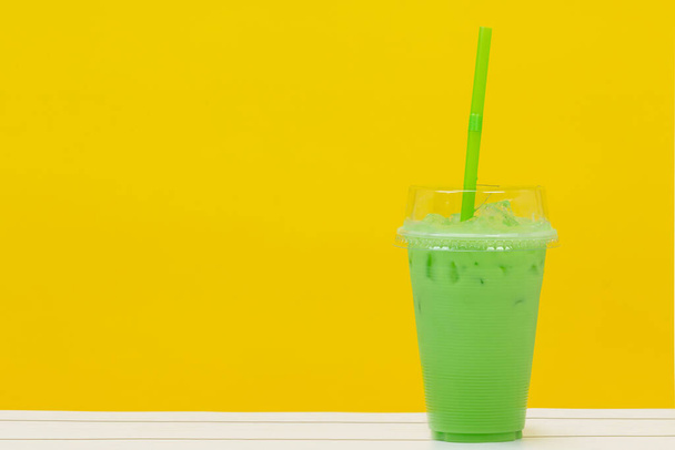 green beverage and green straw on yellow background - Fotoğraf, Görsel