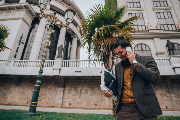 moderne hipster guy avec les cheveux longs et la barbe à la promenade de la ville ayant conversation mobile
 - Photo, image